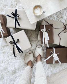 a woman's feet in white slippers with wrapped presents and coffee on the floor