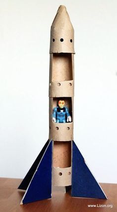 a paper model of a rocket ship with a small figure in the bottom section and an orange toy on top