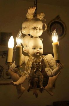 a chandelier with candles in the shape of dolls hanging from it's arms