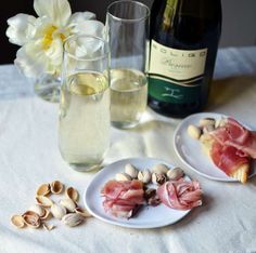 two white plates with food on them next to a bottle of wine and some glasses