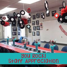 a long table with chairs and decorations hanging from it's ceiling in a classroom