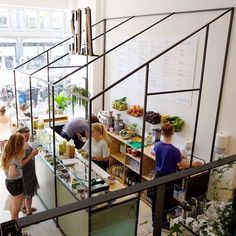 several people are standing in an office with food on the counter and shelves behind them