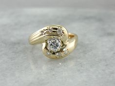 a yellow gold ring with two diamonds on the top and bottom, sitting on a marble surface