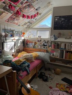 a messy bedroom with lots of clutter on the floor and bookshelves hanging from the ceiling