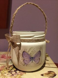 a white jar with a purple butterfly painted on it and some twine around the handle