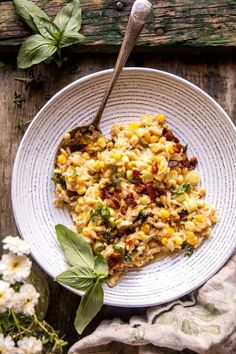 a white bowl filled with pasta and vegetables on top of a table next to flowers