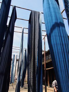 a man is standing in front of some blue cloths hanging from a metal structure