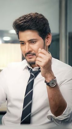 a man with a watch on his left hand is looking at the camera while wearing a white shirt and black tie