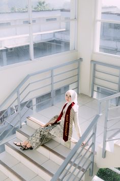 a woman sitting on top of a set of stairs in front of a large window