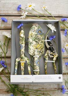 the garden tool set is in a box with blue flowers around it and two scissors