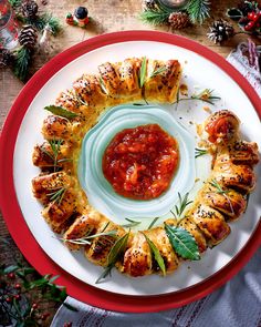 a white plate topped with food on top of a red and white table cloth next to pine cones