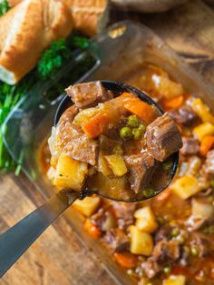 a spoon full of stew on top of a wooden table