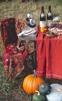 a table topped with bottles of wine next to pumpkins and gourmet food