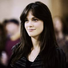 a woman standing in front of a crowd with long hair and wearing a black shirt