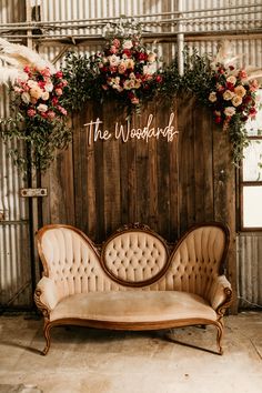 an old couch sitting in front of a wooden wall decorated with flowers and greenery