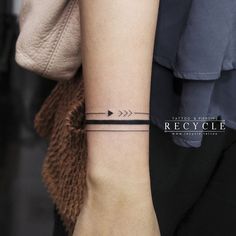 a woman's arm with a black arrow tattoo on it