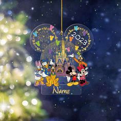 a mickey mouse ornament hanging from a christmas tree with fireworks in the background