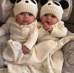 two babies wearing panda hats on top of a blanket