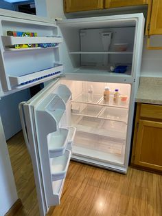 an open refrigerator in a kitchen with wooden floors