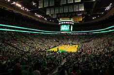 an indoor basketball court filled with lots of green lights and people sitting on the sidelines