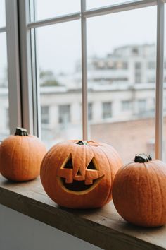 three carved pumpkins sitting on a window sill