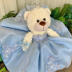 a white teddy bear wearing a blue dress