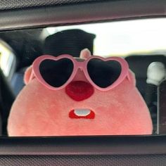 a pink teddy bear with heart shaped sunglasses in the back seat of a car,