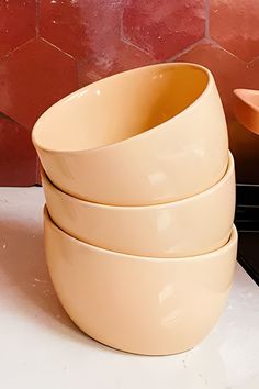 four bowls stacked on top of each other in front of a red brick wall behind them