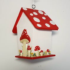 a red and white birdhouse with mushrooms on it