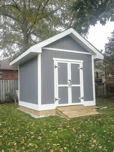 a gray and white shed sitting in the grass