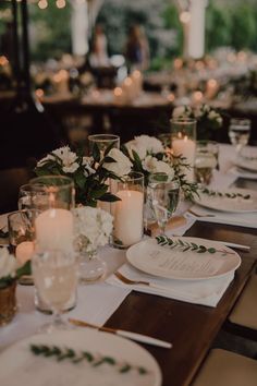 the table is set with white flowers and candles for an elegant dinner party or reception