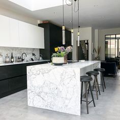 a kitchen with marble counter tops and stools next to an island in the middle