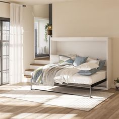 a bed sitting on top of a wooden floor next to a window