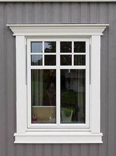 a white window sitting on the side of a gray building