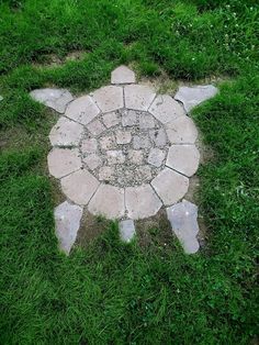 a circular stone table in the middle of some grass with an animal on it's side