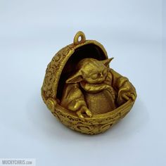 a gold ornament shaped like a baby yoda in a basket with ornate designs