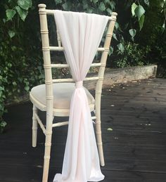 a white chair with a pink sash tied to it's back sitting on a wooden deck