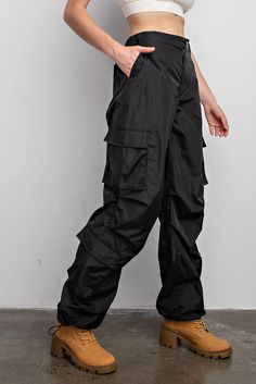 Experience effortless comfort and functionality with our Parachute Cargo Pants. Featuring a zipper with button closure, elastic band for the perfect fit, drawstrings for capri length adjustments, and convenient multiple pockets. Crafted from lightweight, windbreaker fabric for lightweight all-day wear.- Drawstring- Back Pockets- Side PocketsModel is 5'9" and wearing size Small. True to size.Fabric Content: 100% Nylon Functional Parachute Pants For Outdoor Activities, Functional Baggy Bottoms With Multiple Pockets, Utility Bottoms With Functional Drawstring For Outdoor, Utility Bottoms With Functional Drawstring For Outdoor Activities, Nylon Pants With Pockets For Outdoor Activities, Spring Bottoms With Multiple Pockets For Outdoor Activities, Spring Outdoor Bottoms With Multiple Pockets, Black Hiking Pants With Pockets, Sporty Spring Bottoms With Multiple Pockets