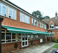 the outside of a brick building with green awnings