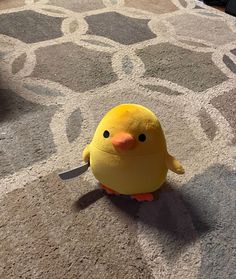 a yellow stuffed animal sitting on top of a carpet next to a knife and fork