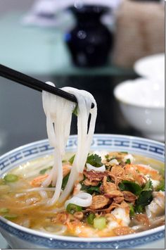 a close up of a bowl of soup with chopsticks sticking out of it