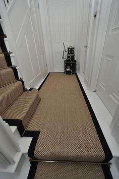 there is a carpeted stair case in the hallway next to some doors and a rug on the floor