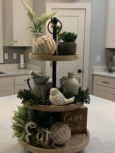 three tiered trays with plants and other items on top of it in a kitchen