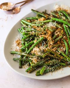 a white plate topped with green beans covered in parmesan