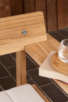 a close up of a wooden table with a glass and book on it next to a tile floor