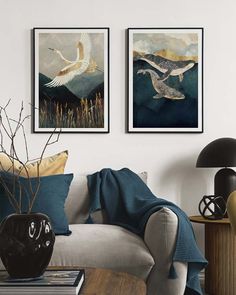 two paintings on the wall above a couch in a living room with a coffee table