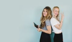 two young women standing next to each other with their hands in the air and smiling