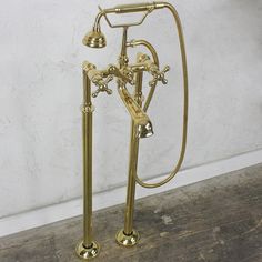 an old fashioned brass faucet and shower head on wooden floor next to wall