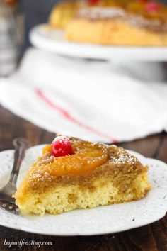 a slice of pineapple upside down cake on a white plate with a fork next to it