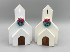 two white wooden church shaped like houses with red bows on the front and blue pom - poms on the back